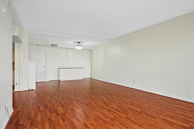 spare room featuring baseboards, a textured ceiling, visible vents, and wood finished floors