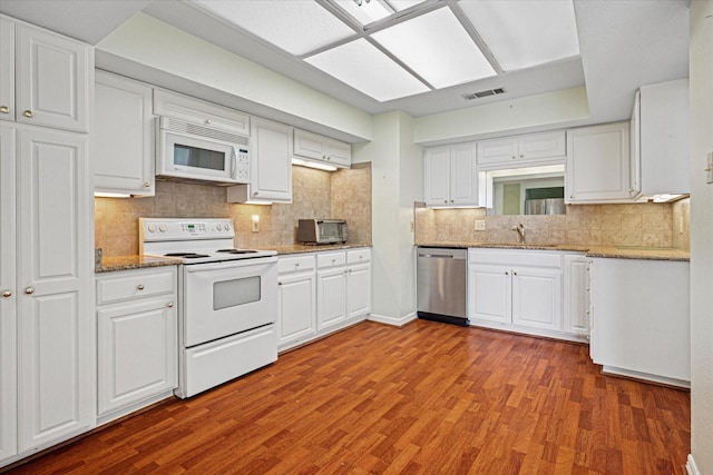 kitchen with white cabinetry, white appliances, a sink, visible vents, and wood finished floors
