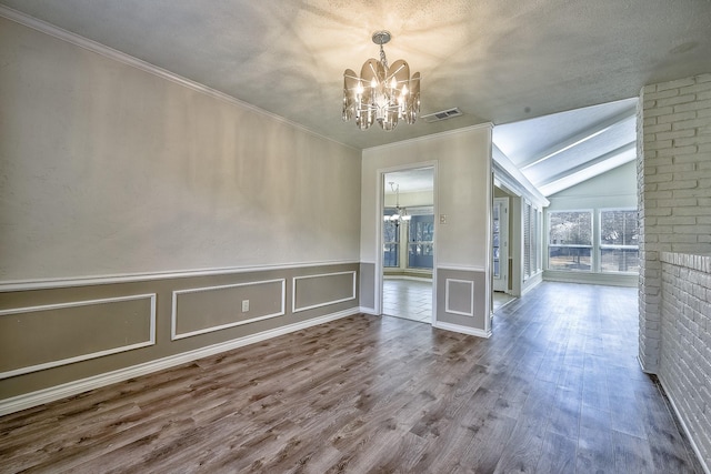 unfurnished dining area with visible vents, wood finished floors, an inviting chandelier, crown molding, and a decorative wall