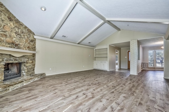 unfurnished living room with a fireplace, wood finished floors, visible vents, and ornate columns