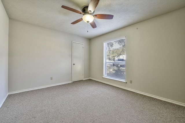 carpeted empty room featuring ceiling fan, baseboards, and a textured ceiling