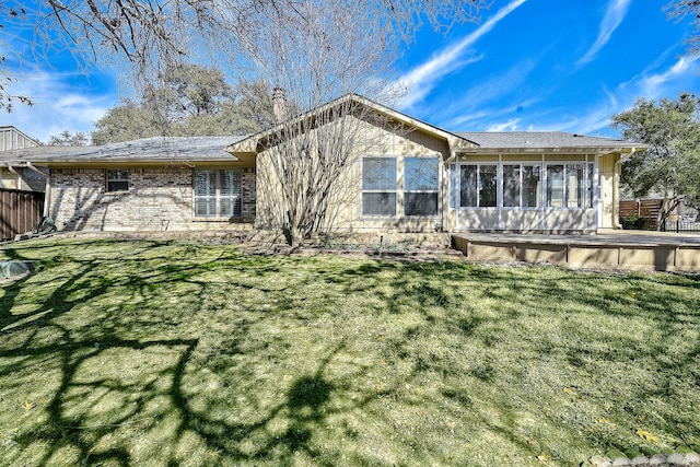 rear view of house featuring a sunroom, a chimney, fence, and a lawn