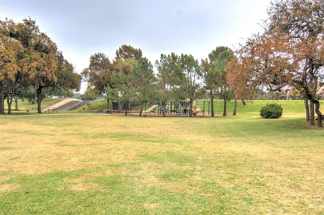 view of property's community featuring playground community and a yard