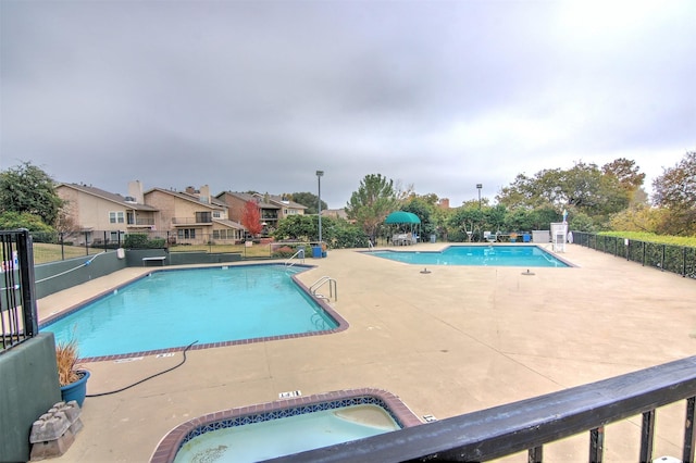 pool featuring a patio area, fence, a residential view, and a hot tub