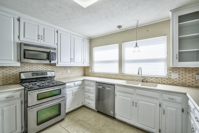 kitchen with decorative light fixtures, stainless steel appliances, light countertops, glass insert cabinets, and white cabinets