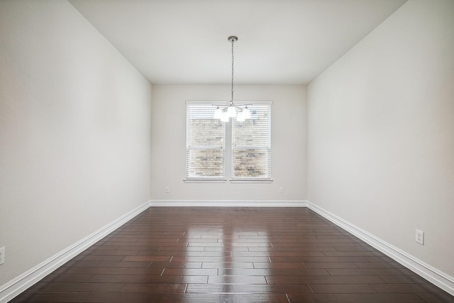 unfurnished dining area with dark wood-style floors, a notable chandelier, and baseboards