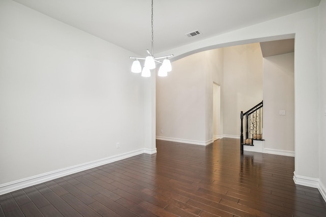 spare room with a chandelier, visible vents, baseboards, stairs, and dark wood-style floors