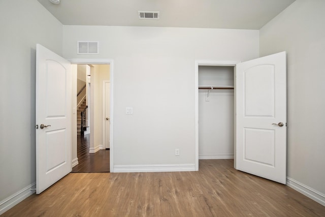 unfurnished bedroom featuring baseboards, a closet, visible vents, and wood finished floors