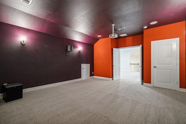 home theater featuring carpet, lofted ceiling, visible vents, a textured ceiling, and baseboards