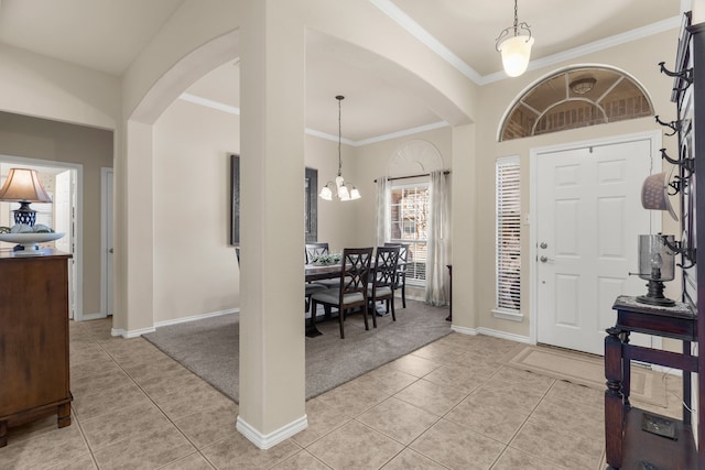 entrance foyer with an inviting chandelier, light tile patterned flooring, light colored carpet, and crown molding