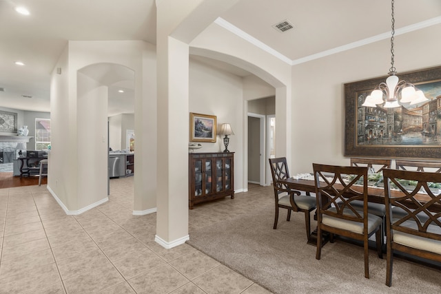 carpeted dining room featuring ornamental molding, arched walkways, tile patterned flooring, and visible vents