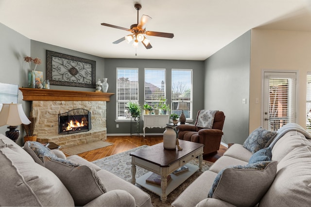 living area with ceiling fan, a fireplace, baseboards, and wood finished floors