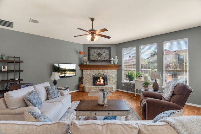 living area with baseboards, visible vents, a fireplace, and light wood finished floors