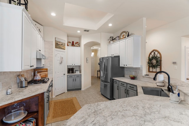 kitchen featuring stainless steel appliances, under cabinet range hood, white cabinetry, open shelves, and a sink