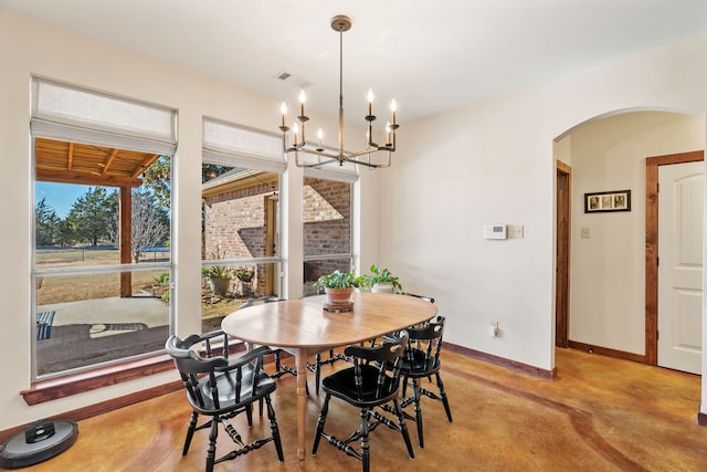 dining space featuring arched walkways, a notable chandelier, visible vents, concrete flooring, and baseboards