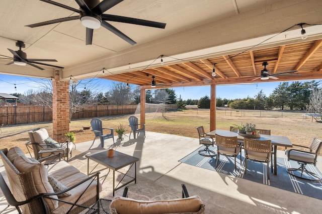 view of patio featuring a fenced backyard, a rural view, a ceiling fan, and outdoor dining space