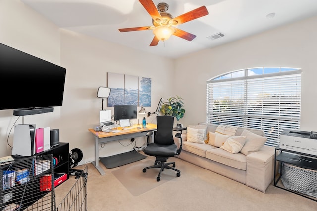 office space with visible vents, a ceiling fan, and light colored carpet