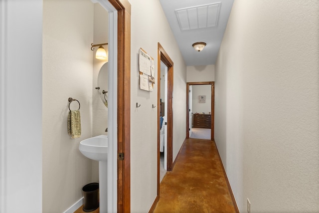 hallway with baseboards, concrete floors, and visible vents