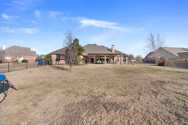 back of property with a yard, a fenced backyard, a chimney, and brick siding