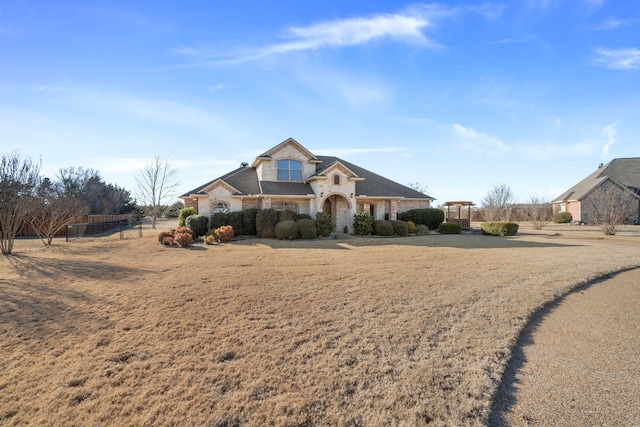 french country inspired facade with stone siding and fence