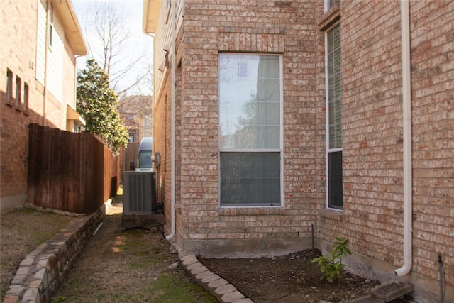 view of property exterior featuring central air condition unit and fence