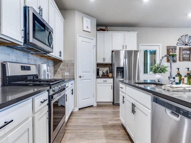 kitchen featuring stainless steel appliances, decorative backsplash, a sink, and white cabinets