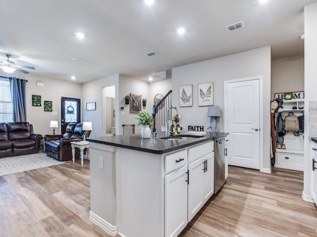 kitchen with dark countertops, visible vents, open floor plan, a sink, and dishwasher