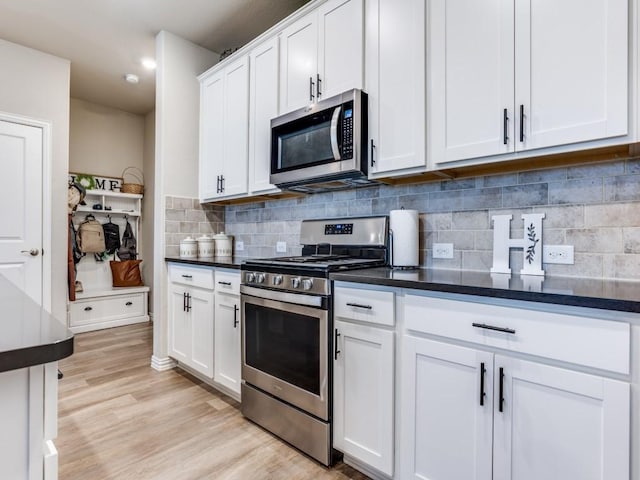 kitchen with stainless steel appliances, white cabinetry, light wood-style floors, and decorative backsplash