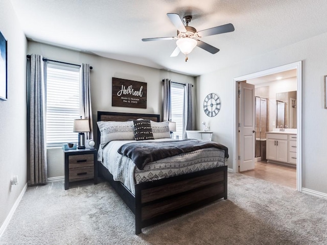 bedroom with a ceiling fan, light carpet, ensuite bath, and baseboards