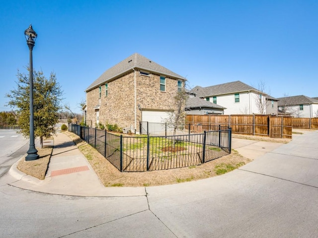 view of front of property with a garage, concrete driveway, fence, and a residential view