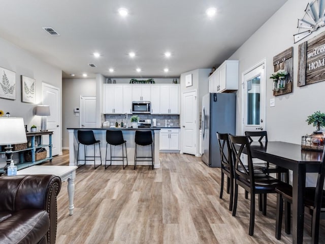 kitchen with open floor plan, appliances with stainless steel finishes, dark countertops, and white cabinetry