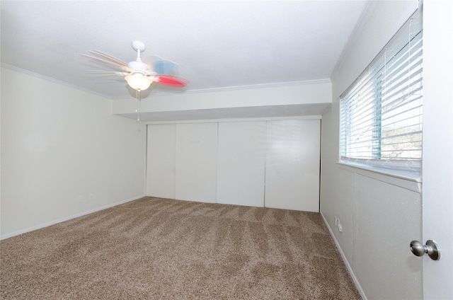 unfurnished bedroom featuring carpet floors, ornamental molding, a closet, and a ceiling fan