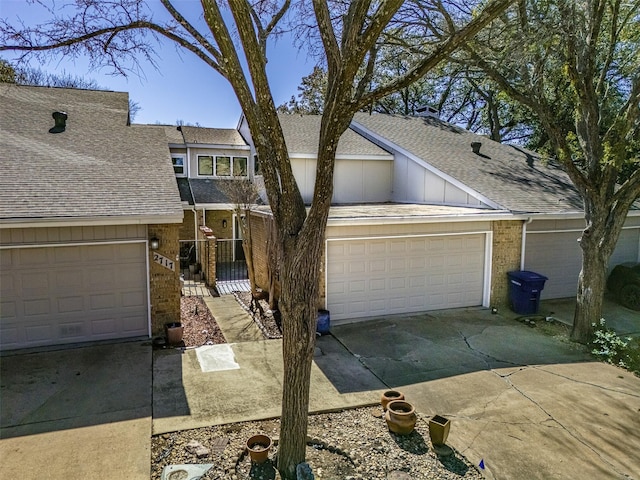 view of front facade with a garage, roof with shingles, concrete driveway, and brick siding