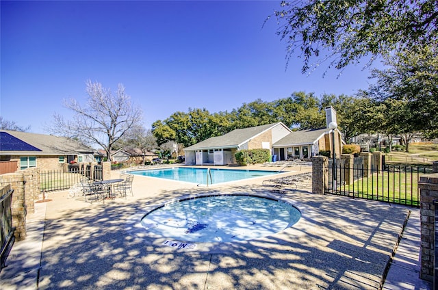 community pool featuring a patio area, a hot tub, a residential view, and fence