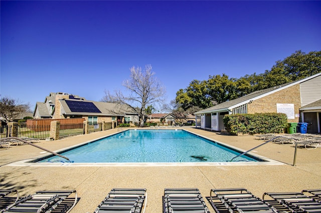 community pool with a patio and fence