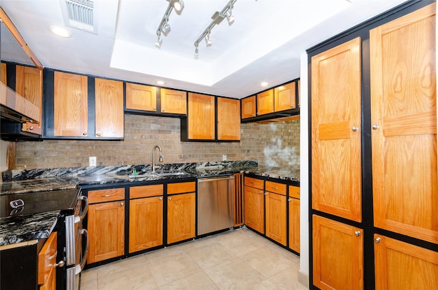 kitchen featuring stainless steel appliances, a sink, visible vents, dark stone countertops, and a raised ceiling