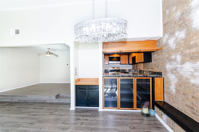 kitchen with dark countertops, a high ceiling, pendant lighting, and dark wood-style flooring