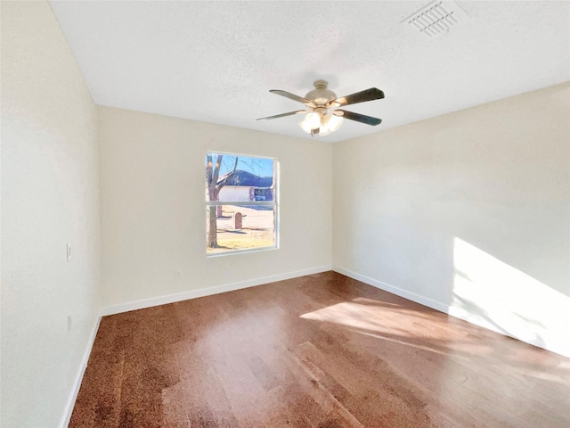 empty room featuring baseboards, visible vents, ceiling fan, wood finished floors, and a textured ceiling