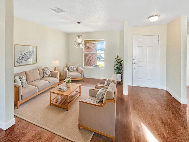 living room featuring a chandelier, wood finished floors, visible vents, and baseboards