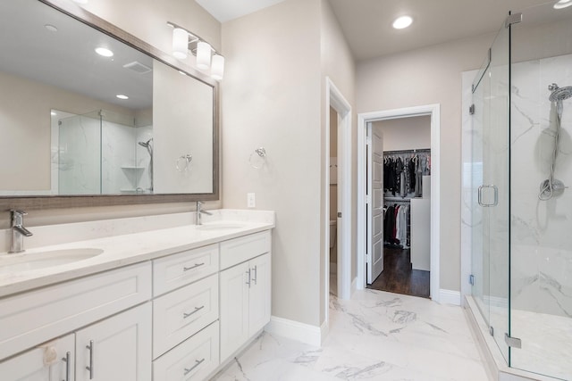 full bathroom with marble finish floor, a marble finish shower, a sink, and a walk in closet