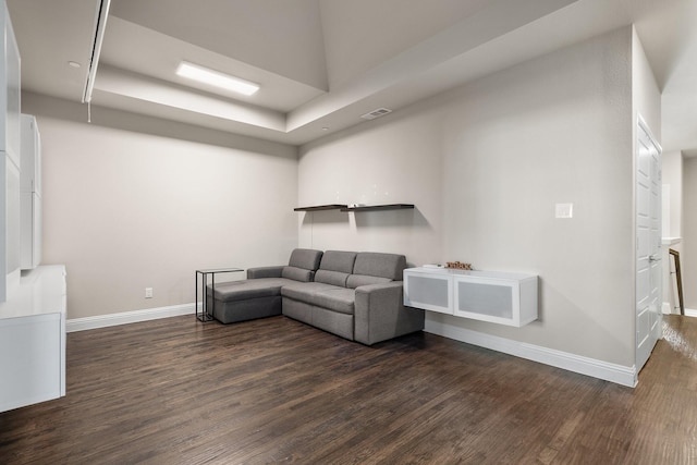 living area featuring dark wood-style flooring, visible vents, and baseboards