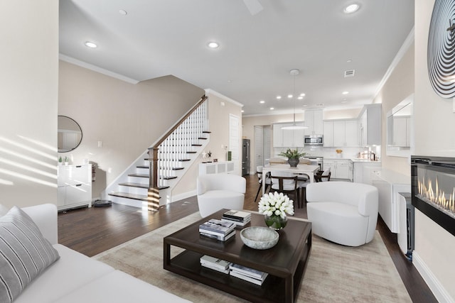 living room featuring light wood-style floors, recessed lighting, ornamental molding, and stairway