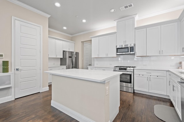 kitchen featuring tasteful backsplash, visible vents, white cabinets, a kitchen island, and appliances with stainless steel finishes