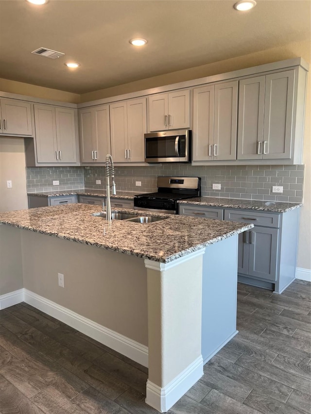 kitchen featuring stone counters, dark wood-style floors, visible vents, appliances with stainless steel finishes, and a sink