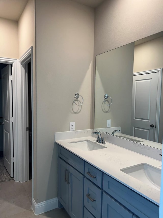 bathroom featuring double vanity, baseboards, and a sink