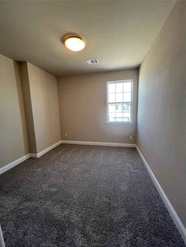 carpeted spare room featuring visible vents and baseboards