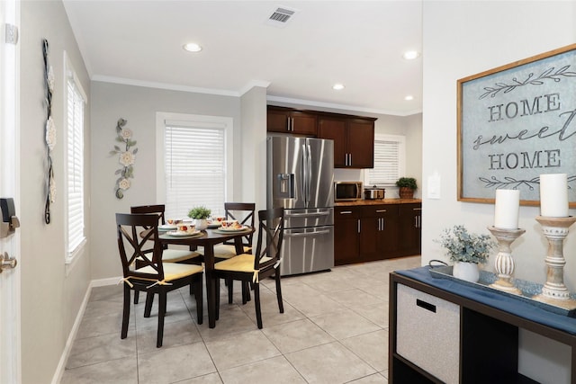 kitchen featuring light tile patterned floors, stainless steel appliances, visible vents, dark brown cabinets, and ornamental molding