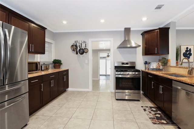 kitchen with visible vents, wall chimney exhaust hood, light stone counters, stainless steel appliances, and a sink