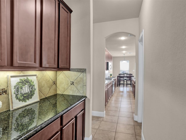 interior space featuring arched walkways, light tile patterned flooring, and baseboards