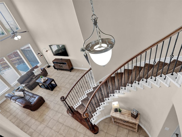 stairway featuring tile patterned flooring, a towering ceiling, and baseboards